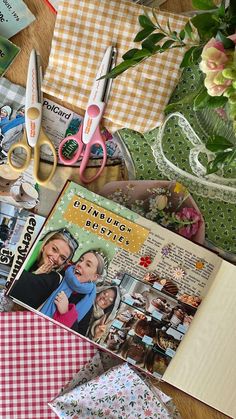 an open book sitting on top of a wooden table next to scissors and other items