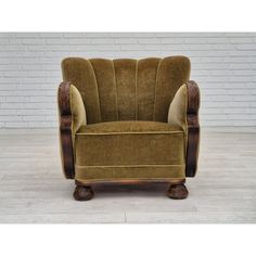 a brown chair sitting on top of a hard wood floor next to a brick wall