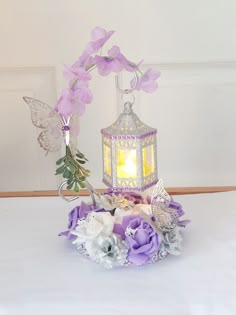 a white table topped with purple flowers and a lantern