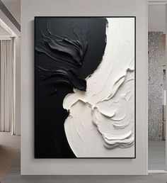 an abstract black and white painting hangs on the wall