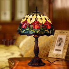 a stained glass lamp sitting on top of a wooden table next to a framed photo