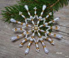 an ornament made out of glass beads on a wooden table next to a pine branch