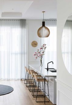 a kitchen with white walls and wooden flooring next to a dining room table filled with chairs