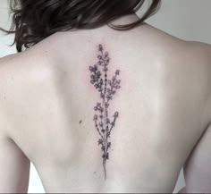 the back of a woman's upper body with flowers on her left shoulder and right arm