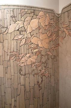 a tiled shower with leaves on the wall