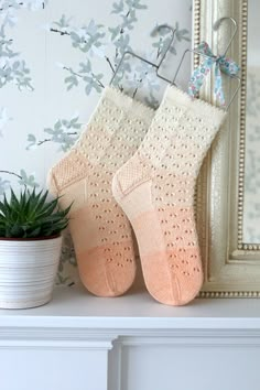 two knitted socks sitting on top of a mantle next to a potted plant