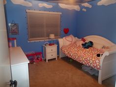 a child's bedroom with blue walls and clouds painted on the wall