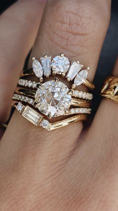 a woman's hand with two gold rings and three diamond wedding bands on it