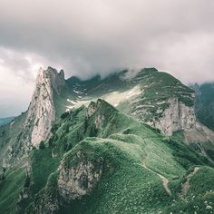 the mountains are covered in green grass and clouds