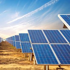 rows of solar panels lined up on the side of a dirt road under a blue sky with wispy clouds