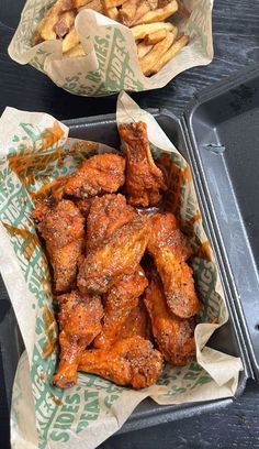 two trays filled with chicken wings and french fries