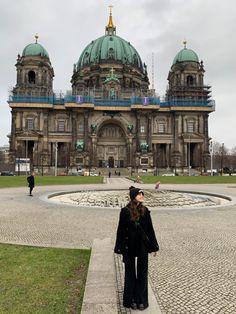 a woman standing in front of a large building with domes on it's roof