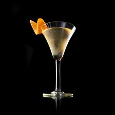 an orange slice is placed on the rim of a martini glass in front of a black background