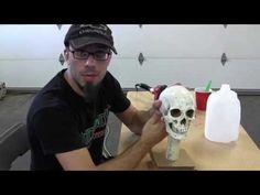 a man sitting at a table with a fake skull in front of him