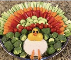 a turkey made out of vegetables and carrots on a platter with dip in the middle