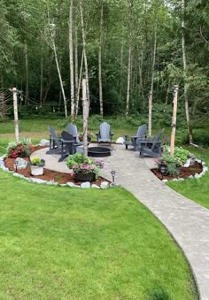 an outdoor patio with chairs and flowers in the center, surrounded by trees on either side