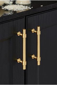 an image of a black and gold cabinet with two handles on the door knobs