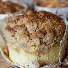 a piece of cake sitting on top of a wooden table next to muffins