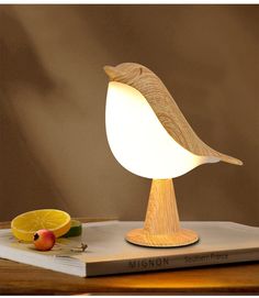 a wooden bird lamp sitting on top of a table next to an apple and lemon