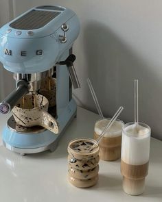 an espresso machine sitting on top of a counter next to two cups