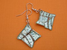 a pair of blue and white square shaped earrings on an orange background with silver earwires