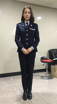 a woman in uniform standing next to a chair