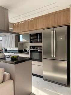 a modern kitchen with stainless steel appliances and marble counter tops, along with white couches