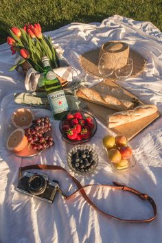 a table topped with food and drinks on top of a white cloth covered field next to a bottle of wine