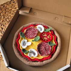 a crocheted pizza in a cardboard box