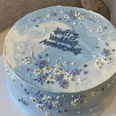 a blue cake with white frosting and flowers on it