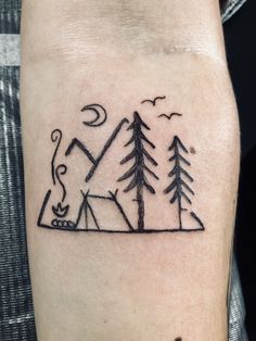 a man's arm with a small tattoo of trees and a tent on it