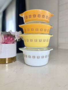 four bowls stacked on top of each other in front of a flower pot and vase