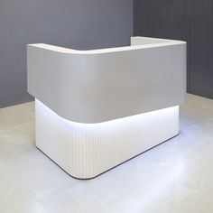 a white reception table with lights on it's sides and a grey wall in the background