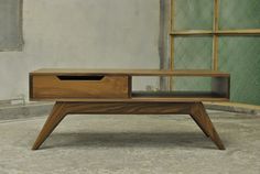 a wooden table with two drawers on it in front of a green wall and window