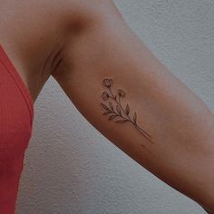 a woman's arm with a small flower tattoo on the left side of her arm