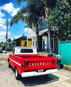 an old red and white chevrolet truck parked on the street in front of a house