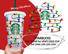 a starbucks cup with christmas lights on it and a hand holding the cup in front