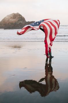 a person holding an american flag on the beach