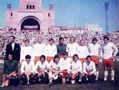 a group of men standing next to each other in front of a stadium filled with people