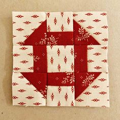 a red and white quilted square with the letter b on it's side