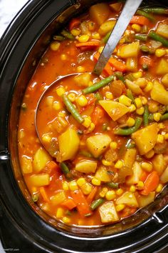 a spoon in a bowl filled with corn and vegetables