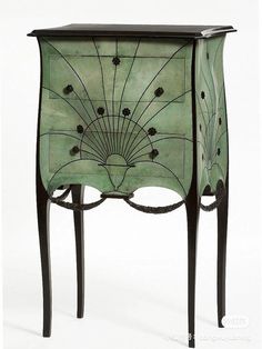 a green cabinet with an intricate design on the front and side panels, painted in black