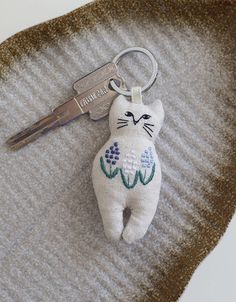 a keychain with a cat on it sitting on top of a piece of fabric