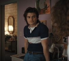 a man standing in front of a mirror wearing a blue and white shirt with stripes on it