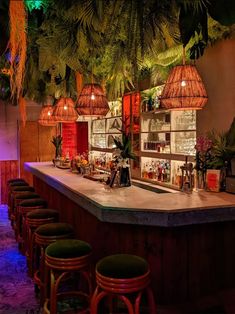 a bar with several stools and lights hanging from it's ceiling in a tropical setting