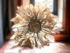 a sunflower made out of newspaper sitting on top of a table