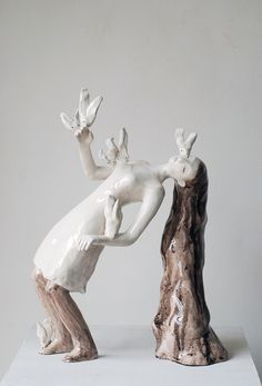 a sculpture of a woman leaning on a tree stump with her hands in the air