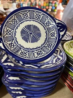 a stack of blue and white plates sitting on top of each other next to bowls