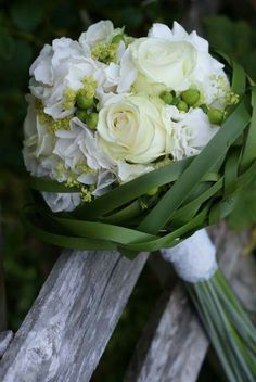 a bouquet of white flowers sitting on top of a wooden rail