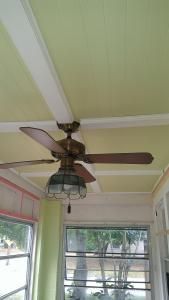 a ceiling fan is hanging from the ceiling in a room with green walls and windows